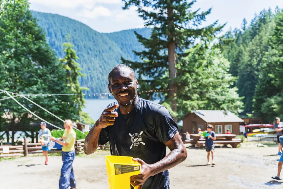 Participante sonriendo en un campamento junto a un lago en Canadá