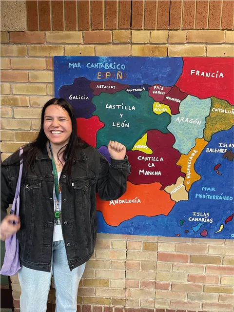 Participante sonriendo junto a un mapa en una sala de idiomas