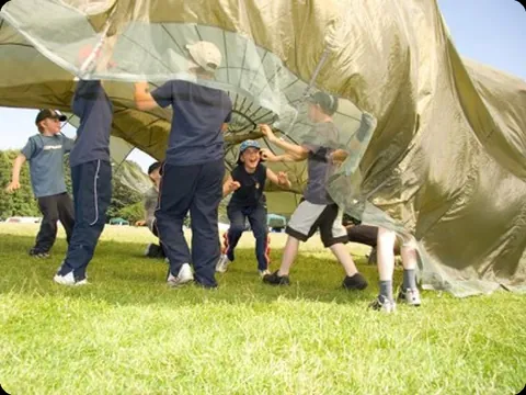 Participantes jugando con un paracaídas de colores en un campamento