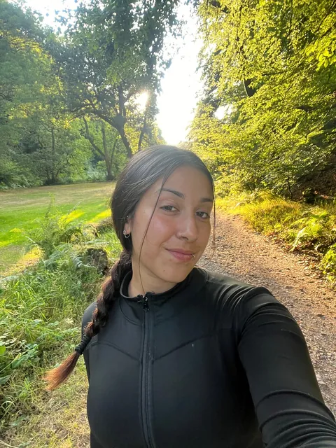 Valentina sonriendo en un sendero arbolado en Inglaterra